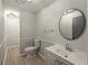 Clean bathroom featuring modern lighting, a round mirror, a toilet, and a sink with vanity for added functionality at 1106 Oak Sw Rd, Lilburn, GA 30047