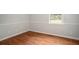 A cozy bedroom with hardwood floors and neutral walls, featuring a window for natural light and a vent for temperature control at 1106 Oak Sw Rd, Lilburn, GA 30047