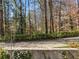 A view of the backyard, with a stone retaining wall, mature trees and greenery at 3200 Wood Valley Nw Rd, Atlanta, GA 30327