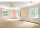 Generously sized bedroom featuring neutral carpet, three windows offering scenic outside views, and ceiling fan at 3200 Wood Valley Nw Rd, Atlanta, GA 30327