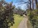 Long driveway through lush greenery leads to property; framed by lawn and trees at 3200 Wood Valley Nw Rd, Atlanta, GA 30327