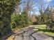View of a long, paved driveway leading to the property, framed by lush greenery and mature trees at 3200 Wood Valley Nw Rd, Atlanta, GA 30327
