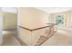 Upstairs hallway with staircase, neutral carpeting, and a large window with scenic outdoor views at 3200 Wood Valley Nw Rd, Atlanta, GA 30327