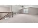 Spacious carpeted bonus room with natural light from the window, and wood and metal railing overlooking a stairway at 1315 Thunder Gulch Pass, Suwanee, GA 30024