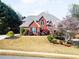 Beautiful red brick two-story home with a manicured lawn and flowering tree in a lovely residential neighborhood at 1574 Stepstone Way, Lawrenceville, GA 30043
