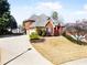 Exterior view of a stately two-story home showcasing lush landscaping and a circular driveway leading to a two-car garage at 1574 Stepstone Way, Lawrenceville, GA 30043