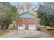 Red brick home exterior with two garage doors, a white door, and green siding at 2330 Bonnybrook Way, East Point, GA 30344