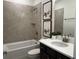 Modern bathroom features a tiled shower and tub combination, complemented by a dark vanity and framed wall art at 325 Sassafras W Way, Holly Springs, GA 30115