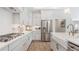 Clean kitchen offers stainless steel appliances, a white farmhouse sink, and bright, white cabinets at 325 Sassafras W Way, Holly Springs, GA 30115