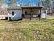 Home back view showcasing a covered porch and grassy yard surrounded by mature trees at 6734 Pass Road, Buford, GA 30518