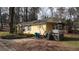 Yellow one-story home featuring a covered porch, set against a backdrop of lush trees at 4622 Dogwood Rd, Pine Lake, GA 30083