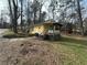 Quaint yellow home with side porch surrounded by trees, with a stone retaining wall visible at 4622 Dogwood Rd, Pine Lake, GA 30083