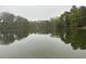 Calm pond reflects the surrounding trees and sky, creating a serene natural scene at 4622 Dogwood Rd, Pine Lake, GA 30083