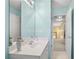 Bright, aqua-colored bathroom featuring a large mirror, vanity, and view to a hallway with a staircase at 3402 Blaisdell Rd, Buford, GA 30519