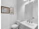 A clean white powder room featuring a pedestal sink, decorative mirror, and framed artwork at 315 Chiswick Cir # 38, Alpharetta, GA 30009
