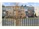 Street view of townhouses with a young tree in front of a wrought iron fence at 4478 Dunblane Ave, Sugar Hill, GA 30518