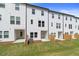 Backyard view of newly built townhomes with white siding, fenced yard, and lawn at 3154 Washburn Sw St, Atlanta, GA 30354