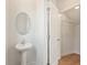 Compact powder room featuring a pedestal sink with an oval mirror and a glimpse of a closet with wood flooring at 984 Sutherland Ln (Lot 31), Lawrenceville, GA 30043