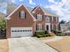 Brick two-story home featuring a two-car garage and manicured landscaping at 602 Kenion Forest Way, Lilburn, GA 30047