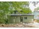 The back of the home is clad in green siding with a dark door, and is shaded by green trees and foliage at 1748 Alvarado Sw Ter, Atlanta, GA 30310