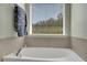 Soaking tub beneath a window in a light and bright bathroom at 690 Floral Pl, Suwanee, GA 30024