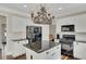 Bright kitchen features an island with a granite countertop, white cabinets, and black appliances at 690 Floral Pl, Suwanee, GA 30024