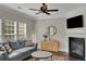 Inviting living room featuring a cozy fireplace, plush sofa, and natural light from large windows at 690 Floral Pl, Suwanee, GA 30024