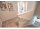Carpeted upstairs hallway and staircase with neutral carpet and wall art at 1027 Northfield Dr, Conyers, GA 30013