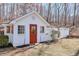 Charming outbuilding with red door, white lattice fence, and mature trees, offering unique space at 3860 Chattahoochee Rd, Cumming, GA 30041