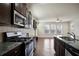 A modern kitchen with dark cabinets, stainless appliances, granite counters, and an open view to the living area at 2463 Turnbury Glen Walk, Snellville, GA 30078