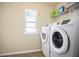Bright laundry room features a front-load washer and dryer, window, and overhead shelving at 2463 Turnbury Glen Walk, Snellville, GA 30078