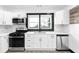 Bright kitchen featuring stainless steel appliances, white cabinets, marble backsplash, and black accents at 1802 S Gordon Sw St, Atlanta, GA 30310