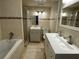 Well-lit bathroom with double sink, shower, bathtub, and neutral tile at 5718 Denson Blvd, Morrow, GA 30260