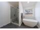 Bright, updated bathroom features a walk-in shower and a modern soaking tub by the window at 7350 Brassfield Dr, Cumming, GA 30041