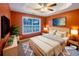 Staged main bedroom featuring a tray ceiling, ceiling fan, large window and two wall-mounted TVs at 175 Stillwood Dr, Fayetteville, GA 30215