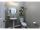 Stylish half bathroom with pedestal sink, round mirror, and decorative shelving at 5620 Berney Cir, Powder Springs, GA 30127