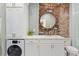 Modern bathroom with exposed brick wall, washer, dryer and white cabinetry at 301 10Th Ne St # 15, Atlanta, GA 30309