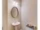 Cozy half bathroom with a pedestal sink, oval mirror, dark accents, and a decorative tray at 4288 Buford Valley Way, Buford, GA 30518