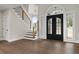 Elegant foyer with dark wood floors, staircase, and arched double doors with transom window at 1066 Fairway Valley Dr, Woodstock, GA 30189