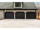 Three car garage with dark doors and matching trim, with sconces over each door at 1066 Fairway Valley Dr, Woodstock, GA 30189
