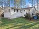 Back exterior of a white home with a sunroom, chimney, lawn, and a shed beneath the deck at 1405 Roper Rd, Canton, GA 30115