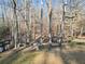 Backyard featuring a swing set, stone table, and various seating options, set against a wooded backdrop at 1405 Roper Rd, Canton, GA 30115