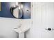 Charming half bath with blue walls, pedestal sink, and modern round mirror at 1405 Roper Rd, Canton, GA 30115