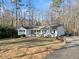 Spacious single-story home with a white exterior, black shutters, and a long driveway surrounded by trees at 1405 Roper Rd, Canton, GA 30115