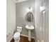 Charming powder room featuring wood flooring, a pedestal sink, and an oval mirror at 2708 Stockbridge Way, Dacula, GA 30019