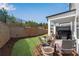 Landscaped backyard with a retaining wall, grass, a covered patio, and a view of the green space behind at 1733 Hyssop Blvd, Mableton, GA 30126