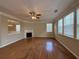 Open-concept living room with hardwood floors, a fireplace, a ceiling fan, and large windows for natural light at 4310 Alysheba Dr, Fairburn, GA 30213