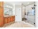 Bright bathroom featuring a glass shower, wood cabinets, granite countertop and wood-style tile flooring at 1030 Chateau Forest Rd, Hoschton, GA 30548