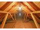 View of the unfinished attic space featuring exposed wood beams and a small window at 2910 Mitchell Ne Cv, Brookhaven, GA 30319