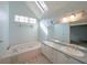 Bright bathroom featuring a soaking tub, dual sinks, a skylight, and large windows at 2910 Mitchell Ne Cv, Brookhaven, GA 30319